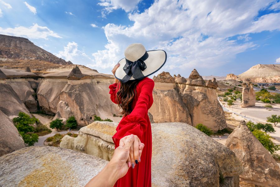 Women tourists holding man's hand and leading him to Fairy Chimneys in Cappadocia, Turkey.